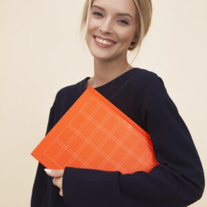 smiling woman standing while holding orange folder